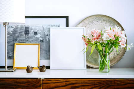 Living room decoration. Framed pictures, flowers and lamp on wooden consoleの写真素材