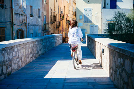 Woman rides a bike in the historical centre of Trapani, Sicily, Italy.の写真素材