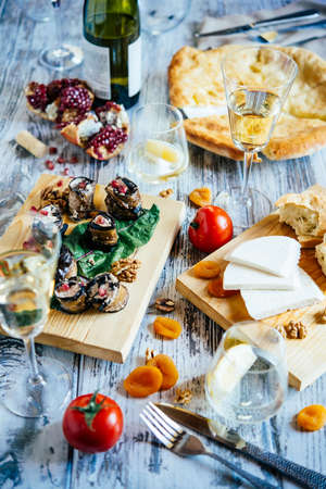 Traditional georgian meals of khachapuri, aubergine rolls, imeretian and suluguni cheeses and wine is served for lunch or dinner on wooden table.の写真素材