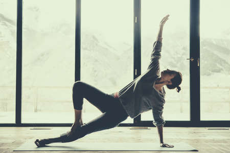 Young beautiful woman practicing yoga with mountain view in the background. Freedom concept. Calmness and relax, woman happiness. Toned pictureの写真素材