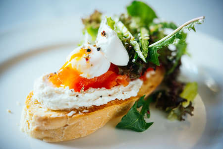 Bruschetta with salmon, quail egg and arugula served on a plateの写真素材
