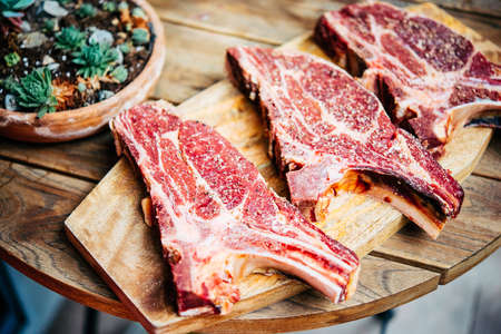 Three aged rib-eye beef meat steaks on wooden board. Grill and BBQ season conceptの写真素材