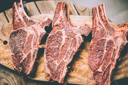 Three aged rib-eye beef meat steaks on wooden board. Grill and BBQ season concept. Toned imageの写真素材
