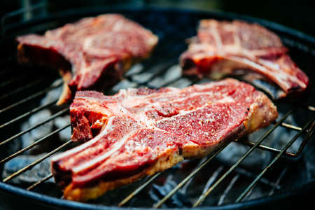 Three aged rib-eye beef meat steaks cooking. Grill and BBQ or barbecue season conceptの写真素材