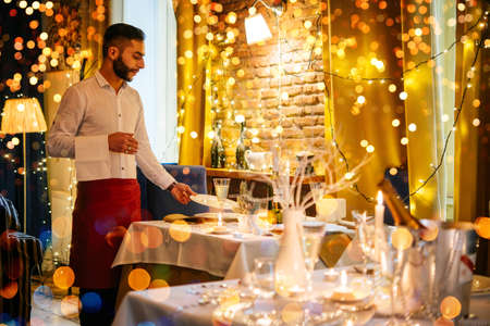 Christmas or New Year party table in a restaurant or cafe.  Waiter is serving tableの写真素材