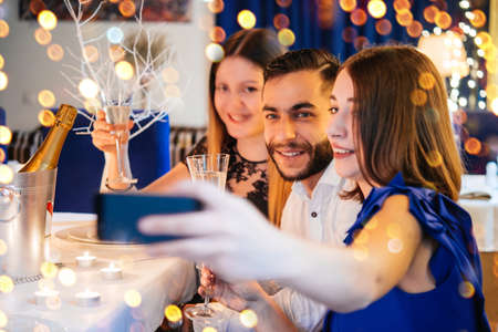 Friends celebrating Christmas or New Year eve. Party table with champagne.の写真素材