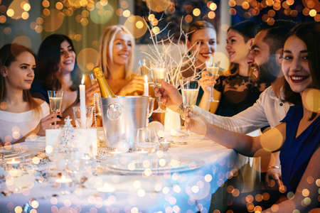 Friends celebrating Christmas or New Year eve. Party table with champagne.の写真素材