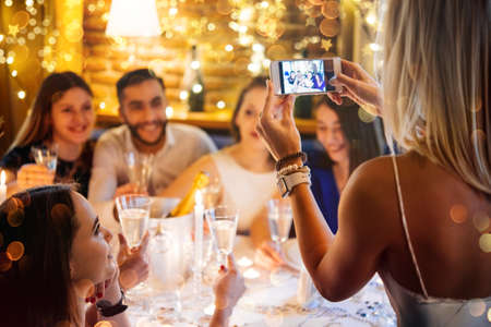 Friends celebrating Christmas or New Year eve. Party table with champagne.