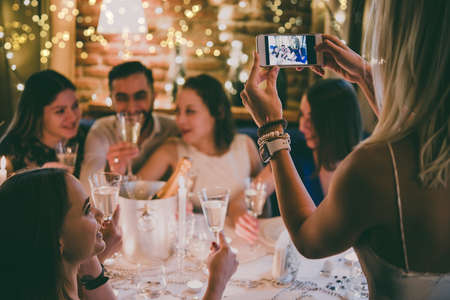 Friends celebrating Christmas or New Year eve. Party table with champagne. Toned pictureの写真素材