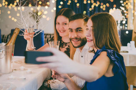 Friends celebrating Christmas or New Year eve. Party table with champagne. Toned pictureの写真素材