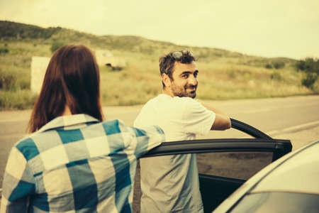Young man and woman stand near their car. Travel and adventure concept. Toned pictureの写真素材