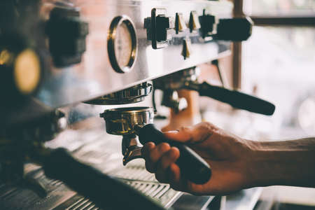 Barista holds a portafilter making coffee with a coffee machine. Toned pictureの写真素材