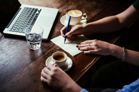 Two women discussing business projects in a cafe while having coffee. Startup, ideas and brain storm conceptの写真素材