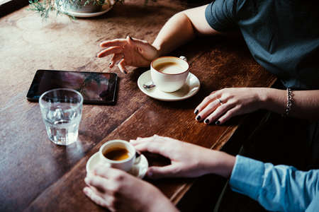 Two women discussing business projects in a cafe while having coffeeの写真素材