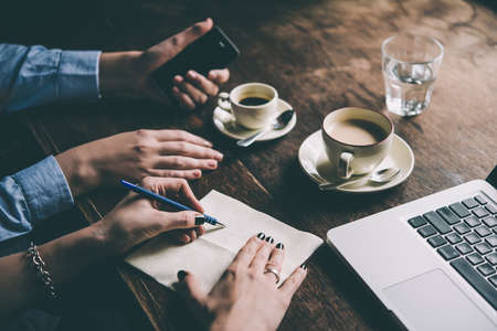 Two women discussing business projects in a cafe while having coffee. Startup, ideas and brain storm concept. Toned pictureの写真素材
