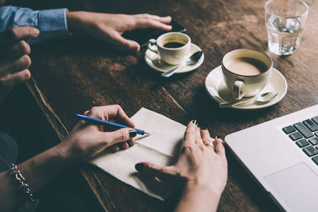 Two women discussing business projects in a cafe while having coffee. Startup, ideas and brain storm concept. Toned pictureの写真素材