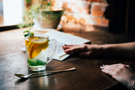 Young woman reads a book while having a cup of hot mint tea or hot lemonade in a cafeの写真素材