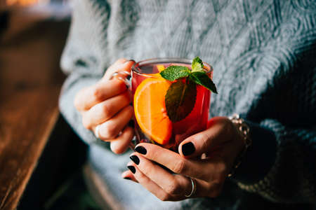 Hands of young woman holding a cup of hot mint tea or hot lemonadeの写真素材