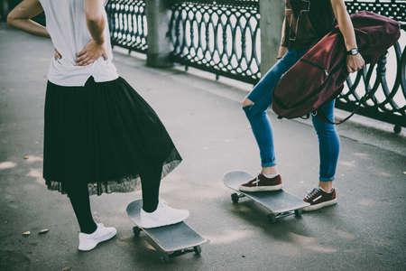 Two young girls enjoy skateboarding in the park in summer. Active live and sport concept. Toned pictureの写真素材