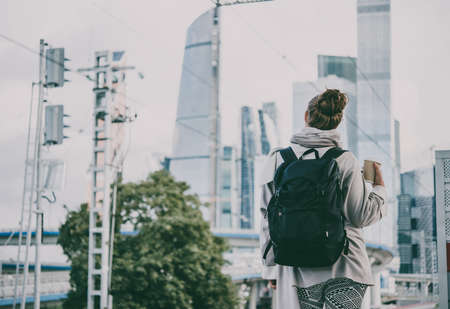Young beautiful woman enjoys the view of Moscow City international business center. Tourism concept. Toned pictureの写真素材