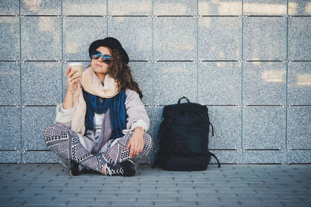 Young beautiful woman sits on the platform while waiting for the train.の写真素材