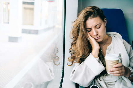 Young sad woman looking through the train window.の写真素材