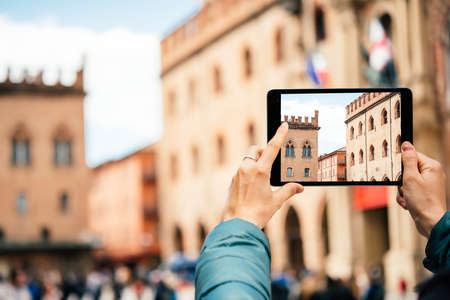 Person uses a tablet to take a picture in the old city of Bologna, Emilia Romagna region, Italy.の写真素材