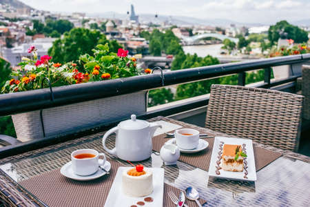 Desserts and tea served in a terrace of restaurant. Tbilisi old city on backgroundの写真素材