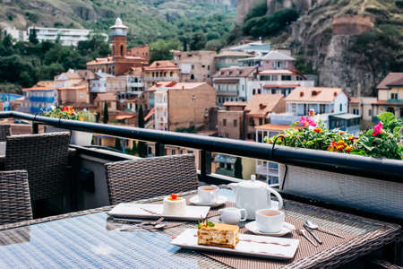 Desserts and tea served in a terrace of restaurant. Tbilisi old city on backgroundの写真素材