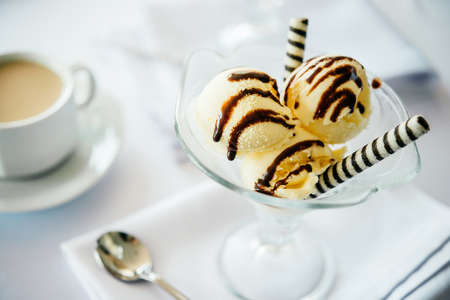 Ice cream with chocolate topping served with coffee and milkの写真素材