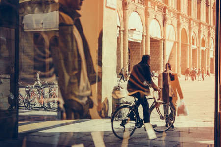 View of piazza Maggiore with the reflections of pedestrians in the windows in the old city of Bologna, Emilia Romagna region, Italy. Toned pictureの写真素材
