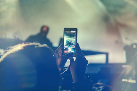 Girl is recording video with smartphone during a concert. Toned pictureの写真素材