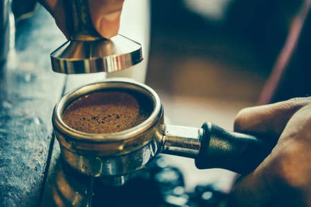 Barista holds a portafilter making coffee with a coffee machine. Toned pictureの写真素材