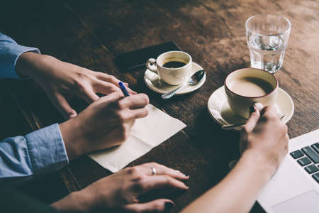 Two women discussing business projects in a cafe while having coffee. Startup, ideas and brain storm concept. Toned pictureの写真素材