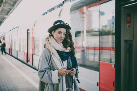 Young beautiful woman stands on the platform while waiting for the train. Toned pictureの写真素材