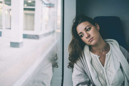Young sad woman looking through the train window. Toned pictureの写真素材