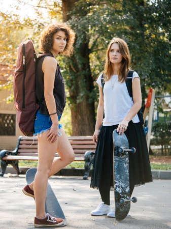 Two young girls enjoy skateboarding in the park in summer. Active live and sport conceptの写真素材