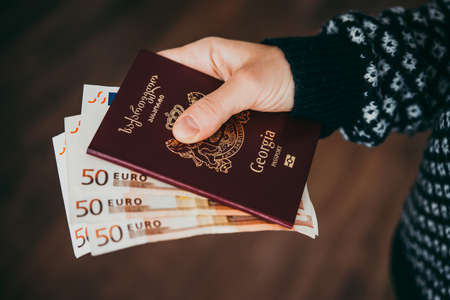Hand holding passport of Georgia and euro billsの写真素材