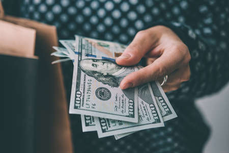 Hands holding dollar bills and paper bags. Shopping concept. Toned picture