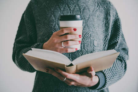 A book and a cup of coffee in hands. Toned imageの写真素材