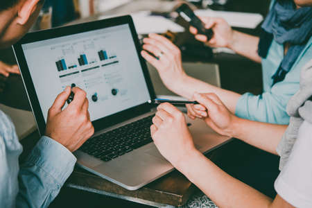 Young creative managers analyzing financial charts and graphs on a laptop. Successful teamwork and business brainstorm concept. Toned imageの写真素材