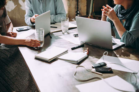 Laptop, mobile phone, tablet and documents on a working table in creative office. Successful teamwork and business startup concept.の写真素材