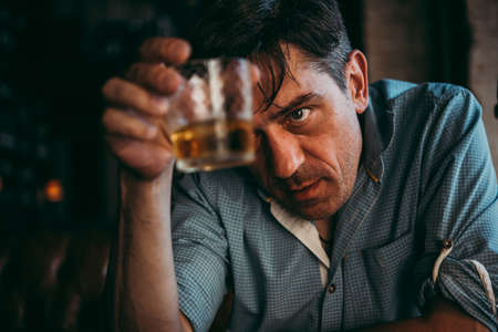 Mature handsome man having a drink. Sadness or depression concept.の写真素材