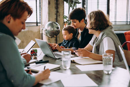 Young business women working together in creative coworking space. Successful mother with baby at workの写真素材