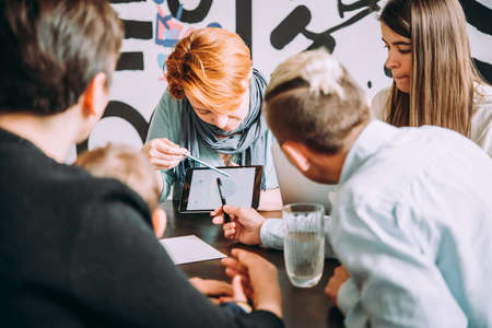 Young woman giving a presentation with tablet in creative office. Successful feminine teamwork and business brainstorming concept.の写真素材