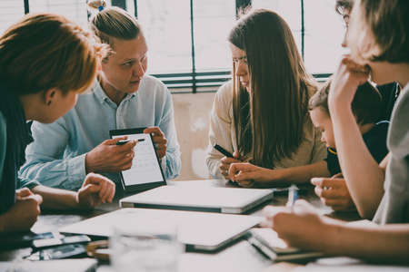 Young woman giving a presentation with tablet in creative office. Successful feminine teamwork and business brainstorming concept. Toned imageの写真素材