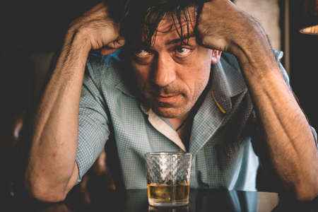 Mature handsome man having a drink. Sadness or depression concept. Toned pictureの写真素材
