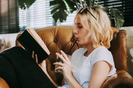 A teenage girl is reading book in an armchair
