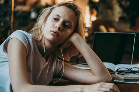 A teenage girl listening to music instead of reading books and doing school homework....