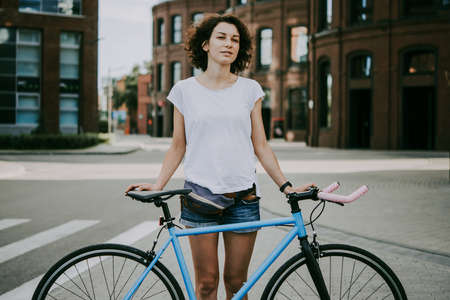 Young beautiful girl stands with her single speed of fixed gear bicycle in the city.の写真素材